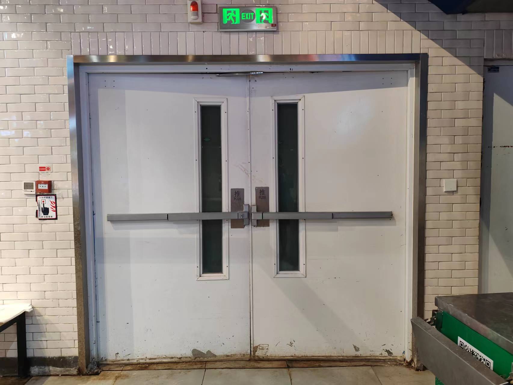 七鲜超市清河万象汇店安全出口的推闩式门锁和白色铁门上,没有标注