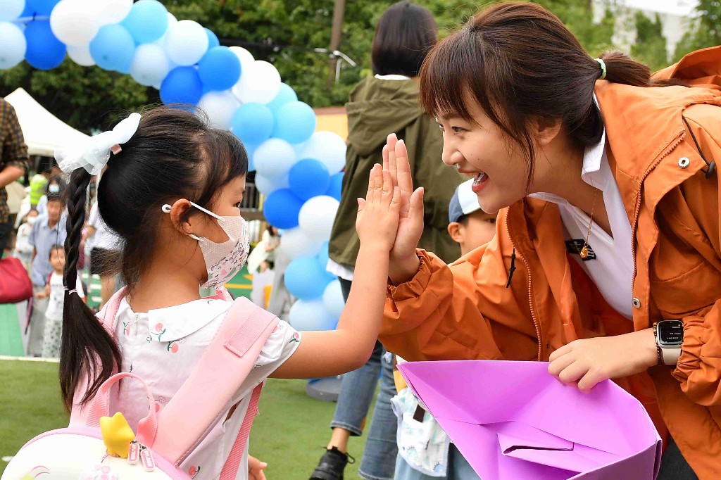 区金钥匙幼儿园新学期开学入园迎接仪式上,一名小朋友向老师击掌致意