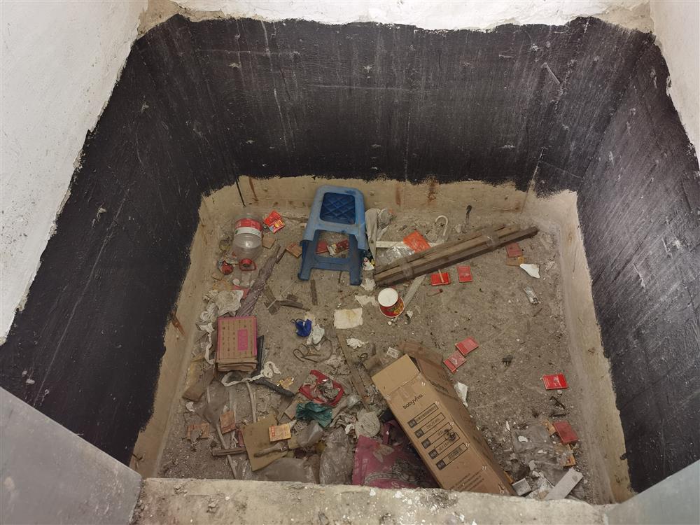 电梯井坑底砂石裸露,有不少生活垃圾扔在里面,看来电梯井如此暴露已有