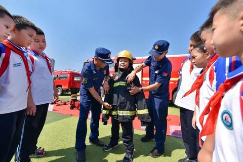 8月31日,在山东邹平市黄山实验小学,小学生体验穿着消防救援服.