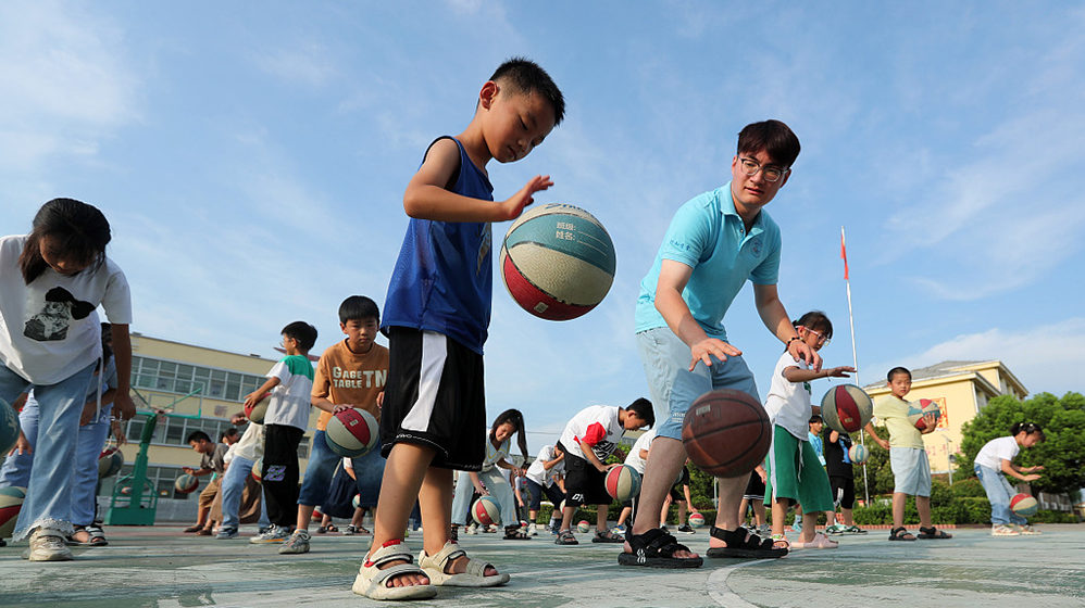安徽蒙城,许疃镇中心小学操场,参加暑期社会实践活动的大学生向小学生
