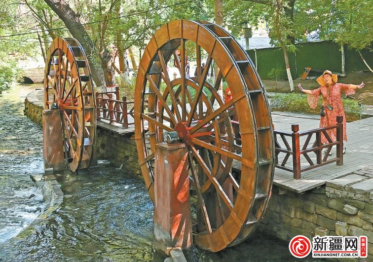 9月8日,在水磨沟公园水磨坊景点,游客正在水车前拍照打卡.