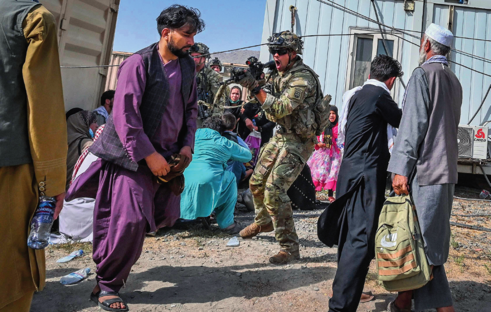 在阿富汗喀布尔机场,一名美军士兵用枪指向一名阿富汗男子(2021年8