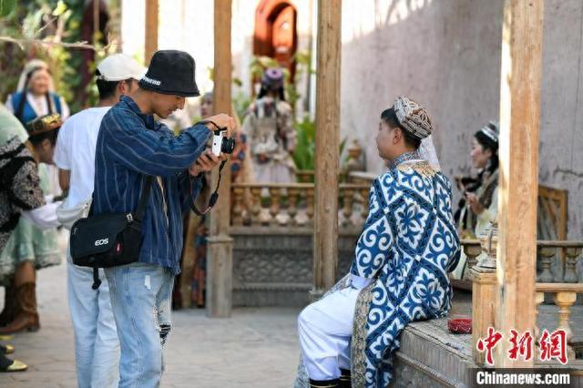 图为在喀什古城景区里一处网红打卡点旅拍摄影师正在拍摄