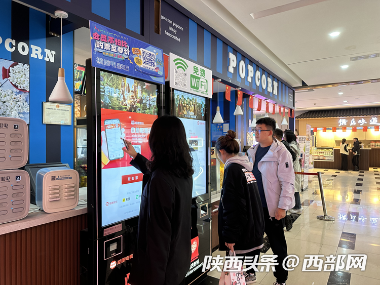 横店电影城西安中贸店自助取票机前,观众排队取票.