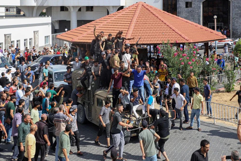 10月7日，在加沙城，巴勒斯坦人登上一辆以色列军用车辆。新华社发（里泽克·阿卜杜勒贾瓦德摄）