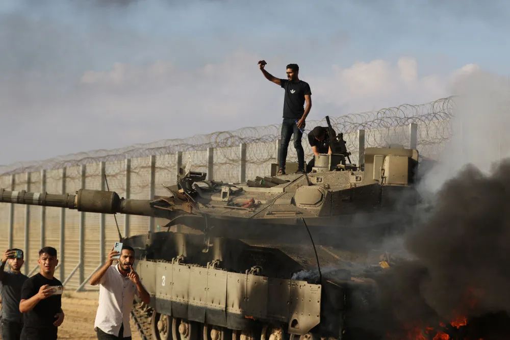 10月7日，在加沙地带城市汗尤尼斯以东的边境地区，巴勒斯坦人出现在一辆以色列坦克附近。新华社发（亚西尔·库迪摄）