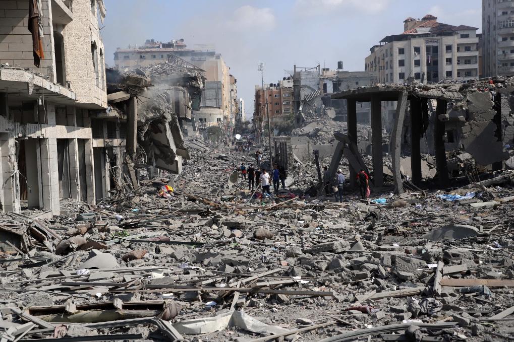 10月10日,在加沙城,人们查看被以色列空袭炸毁的建筑废墟.