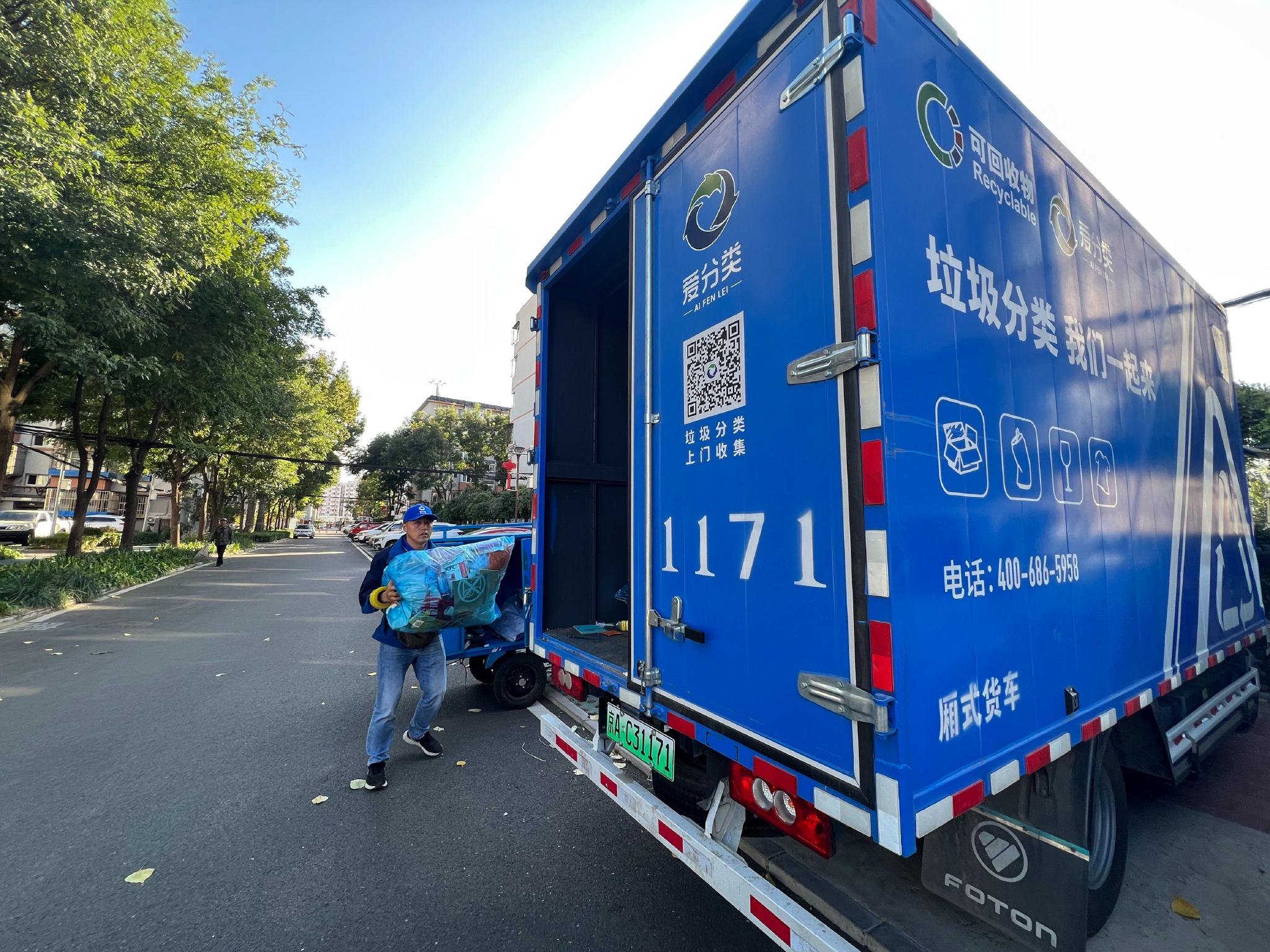 周东芬将称重后的可回收物搬上停放在小区内的蓝色可回收物垃圾转运车