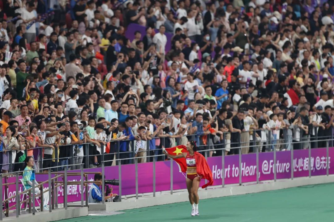 获得女子100米比赛金牌后,中国选手葛曼棋身披国旗向现场观众致意.