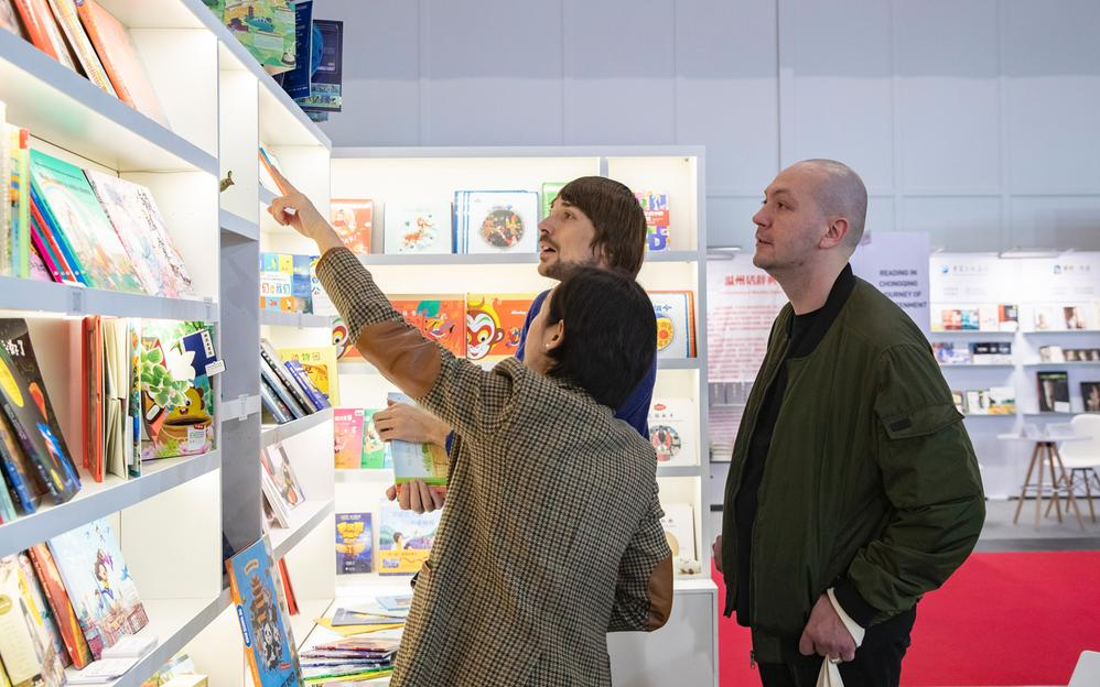 10月18日,在德国法兰克福书展中国展区,参展商向参观者介绍中国图书.