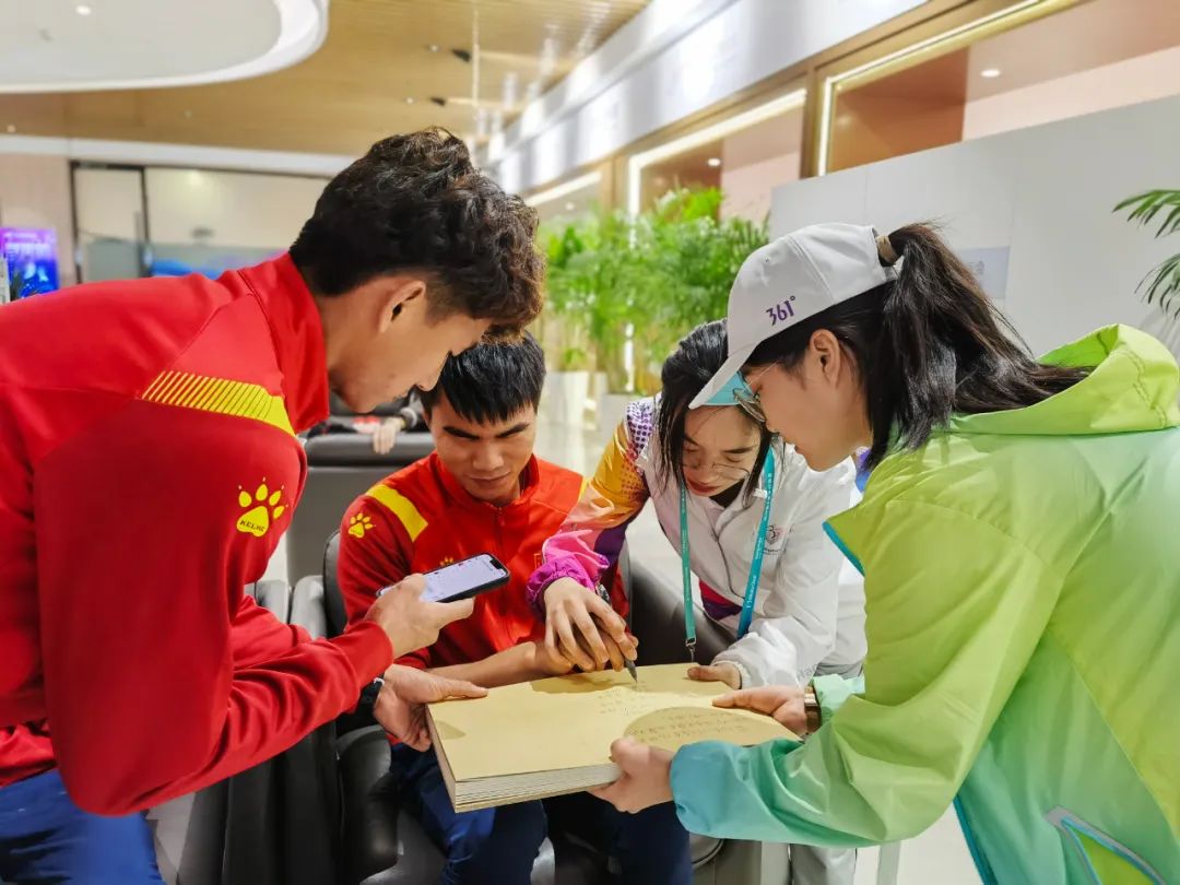 志愿者握着视障运动员的手为赛事写下祝福语.