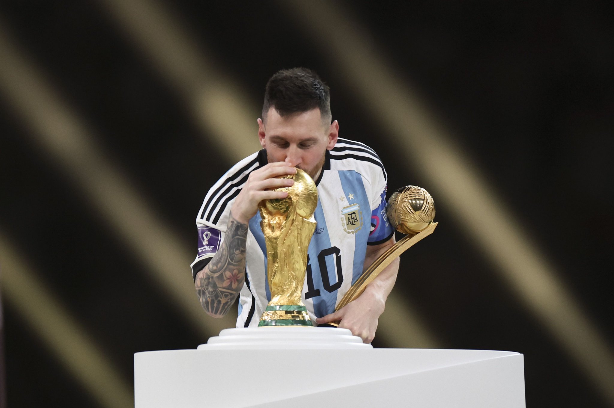 2022年12月18日,获得世界杯金球奖的梅西在颁奖仪式上亲吻大力神杯