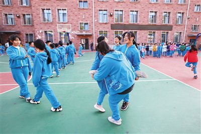 11月7日,东四七条小学操场上,女生围在一起玩"编花篮"游戏.