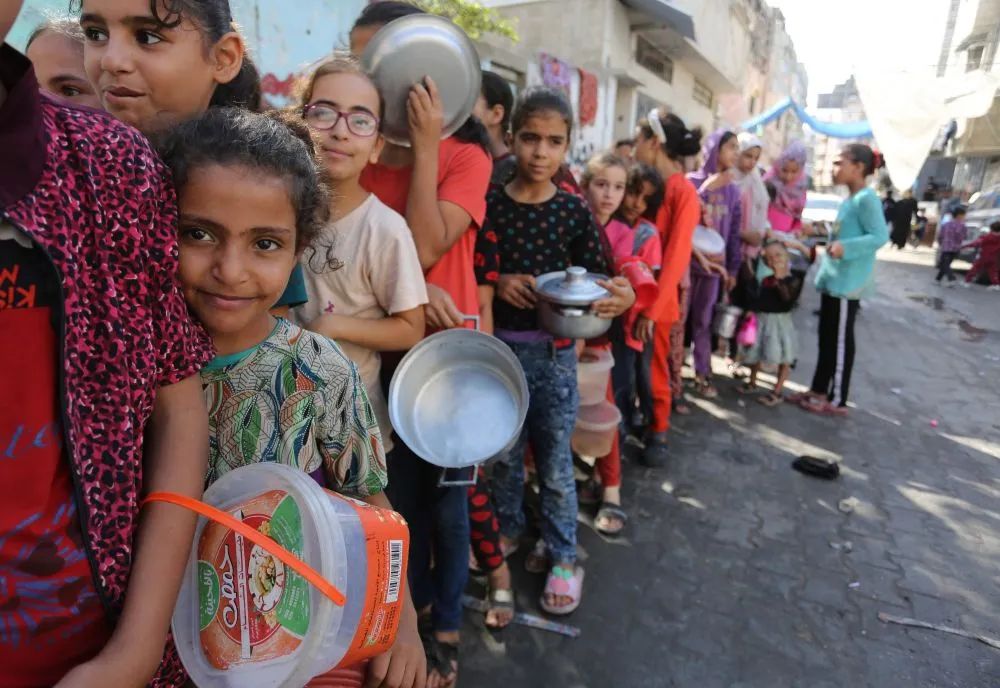 11月9日,在加沙地带南部城市拉法,人们在一个临时分发点排队领取食物.