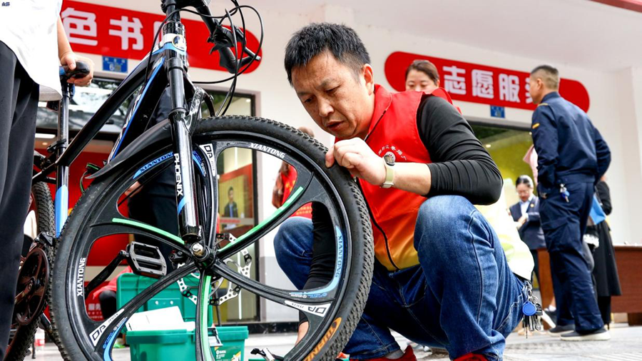 图为便民服务节现场,志愿者为群众修理自行车.