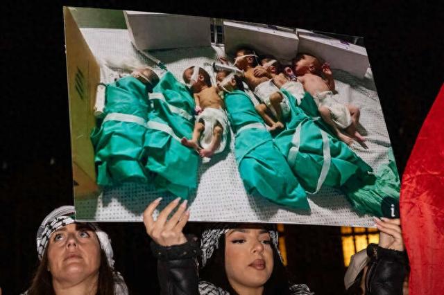 11月15日，英国伦敦，抗议者手持希法医院中新生儿的照片，呼吁加沙停火。图片来源 视觉中国
