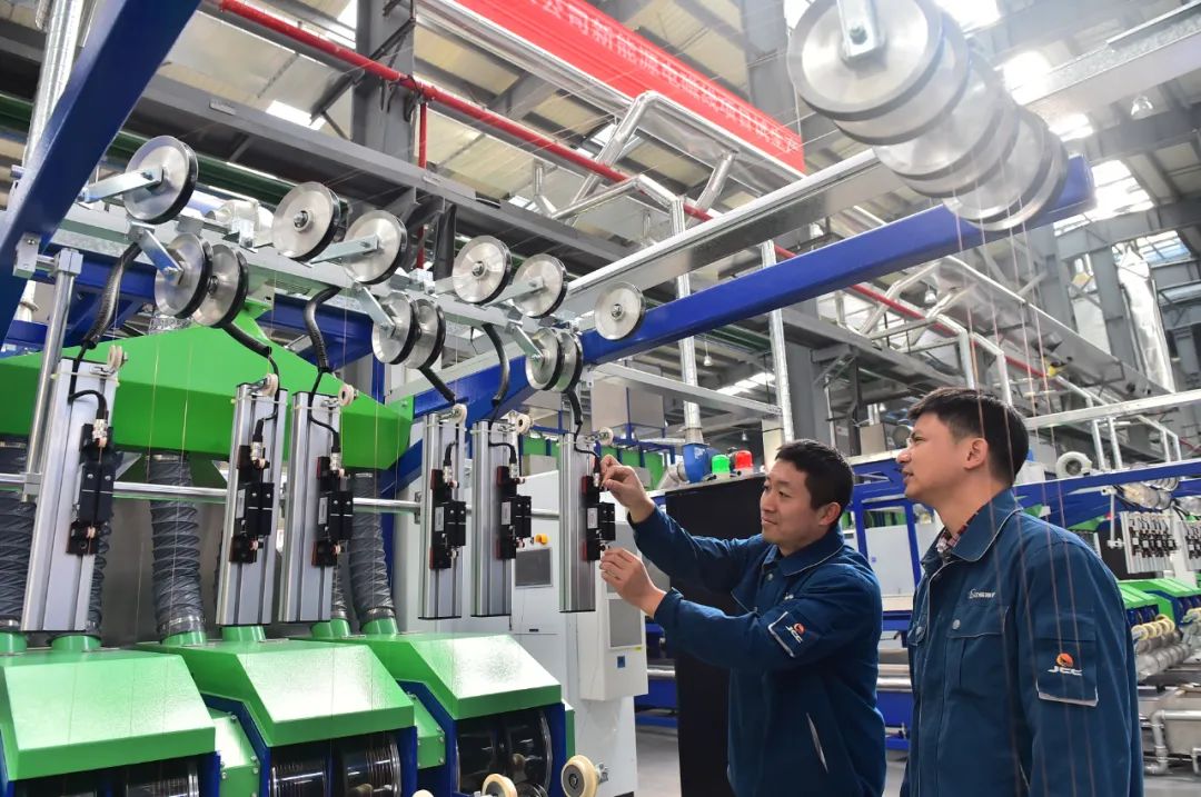 华东电工新材料科技有限公司生产车间,技术工人在生产线上巡检设备