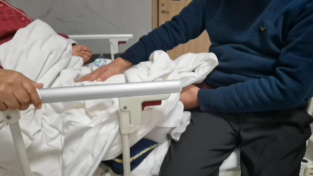 妻子生病住院,老人在病床前陪护悉心按摩
