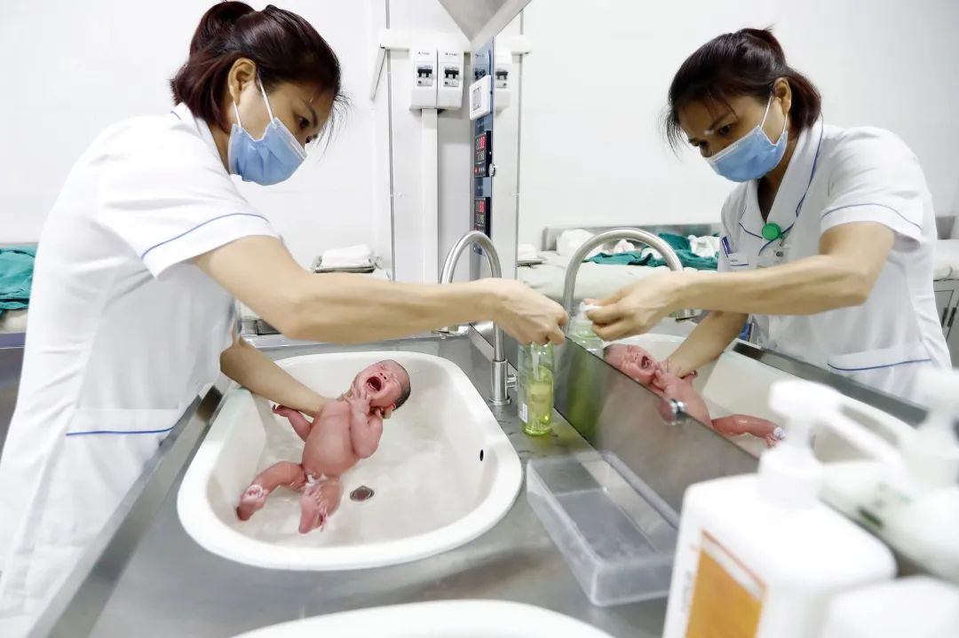 当地时间2023年7月11日，越南河内，一名护士在医院为一名新生儿洗澡。IC photo 资料图