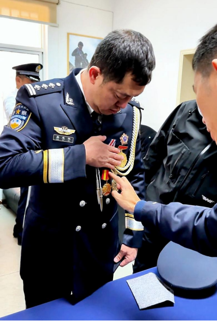 龚志华(左)在拍照现场给年轻民警讲起勋章的由来.