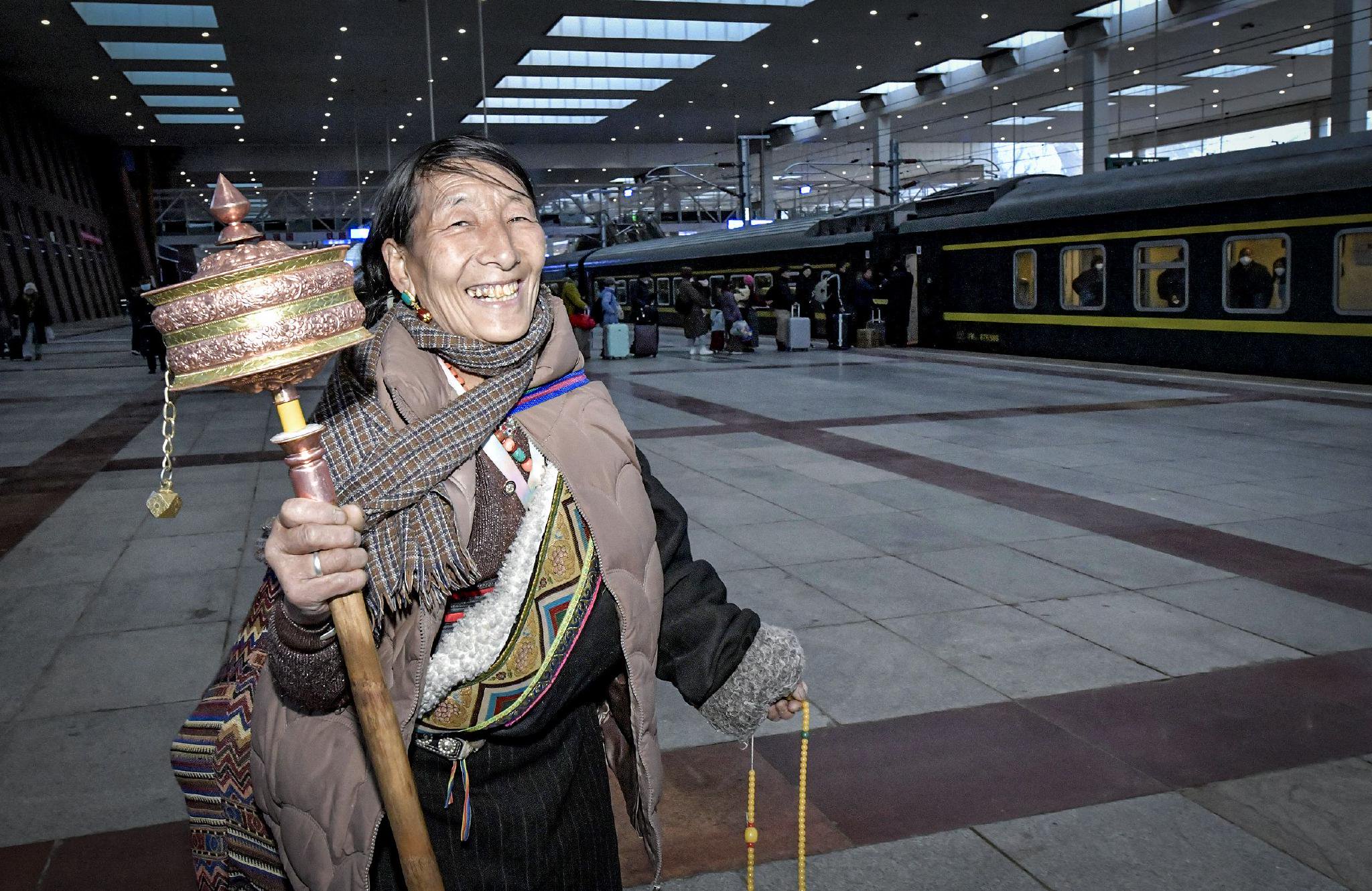 1月26日,拉萨火车站内,手持转经筒的泽让措准备登上开往西宁的z8982次