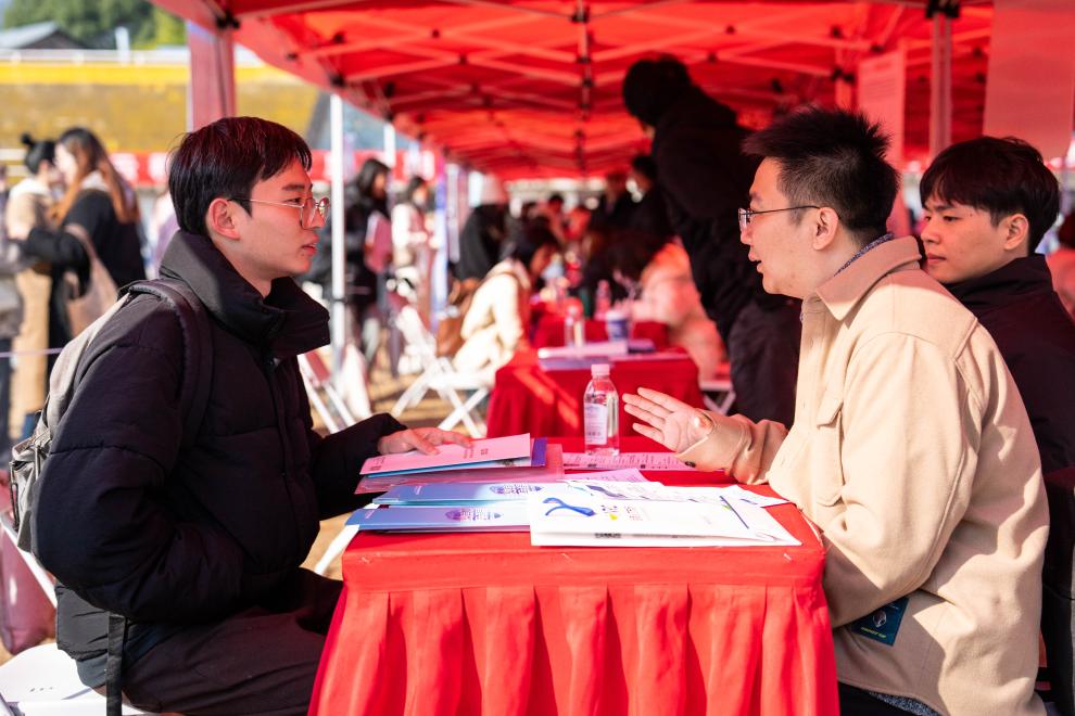 2023年12月1日,在湖南师范大学体育场,求职学生(左)在进行面试.