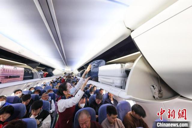 1月28日，从厦门至北京的国航CA1832次航班接近满员，乘务员在飞机起飞前帮旅客摆放行李。记者 贾天勇 摄