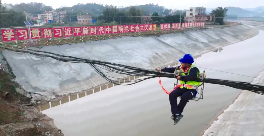 电信施工人员在加固临时迁改的跨河光缆杆线.