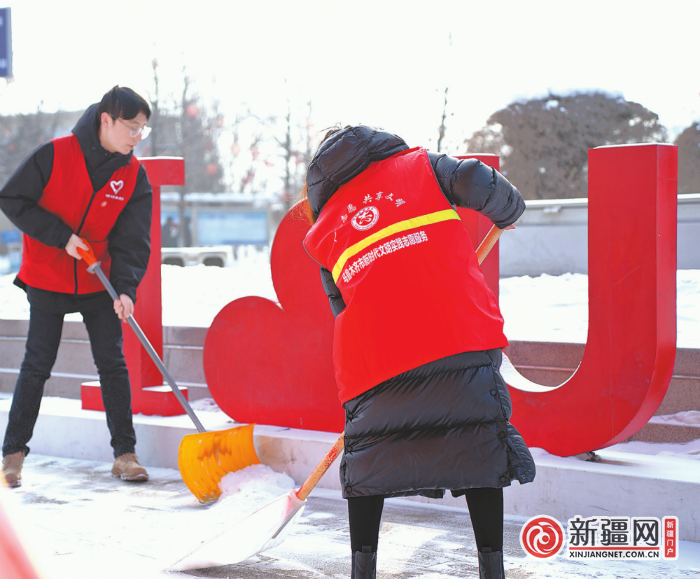 2月3日上午，在乌鲁木齐站站前广场，志愿者正在清扫路面积雪。（全媒体记者王艳红摄）