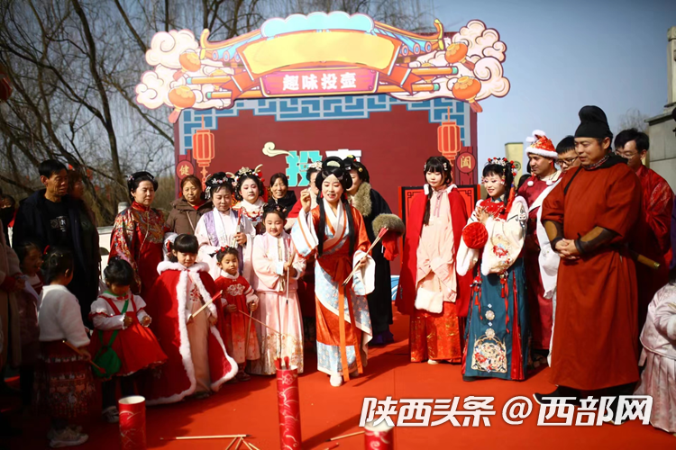 在西安汉城湖景区里,游人着汉服进行趣味投壶活动.