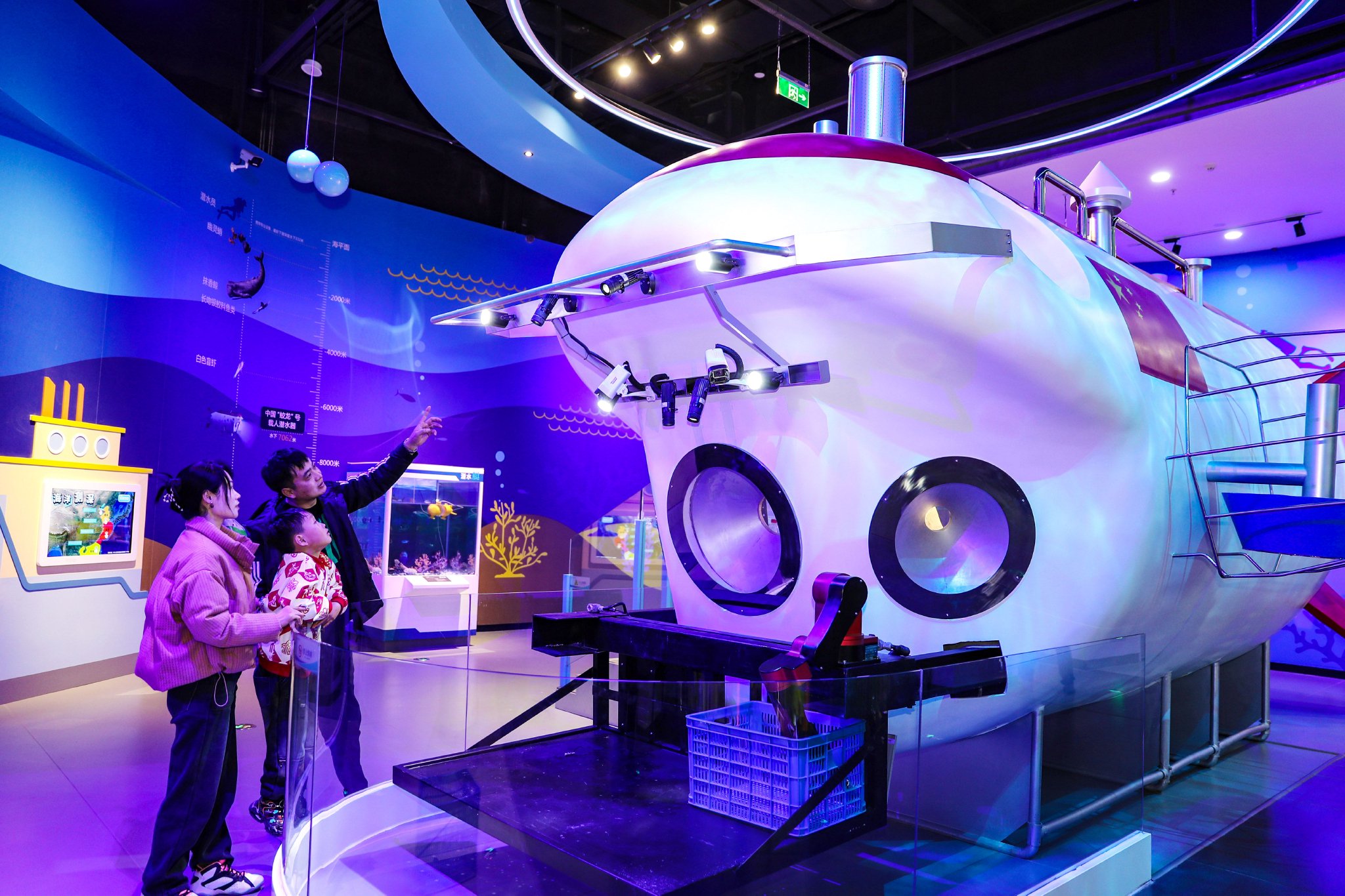 2月14日,在青岛西海岸科技馆,一家三口在参观"蛟龙"号模型.张进刚 摄