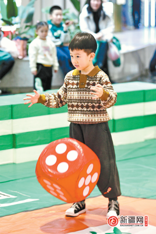 2月15日,在mm3美美购物中心,小朋友在摇巨型骰子参与游戏.