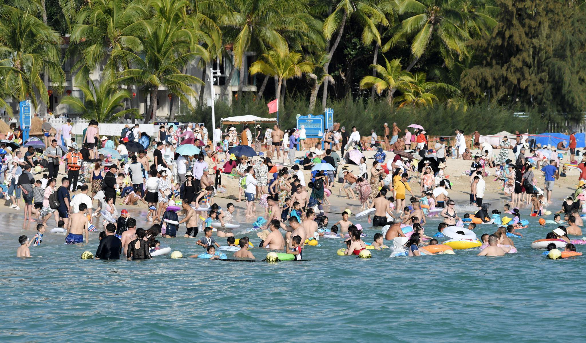 2月13日,游客在海南省三亚市大东海景区戏水.