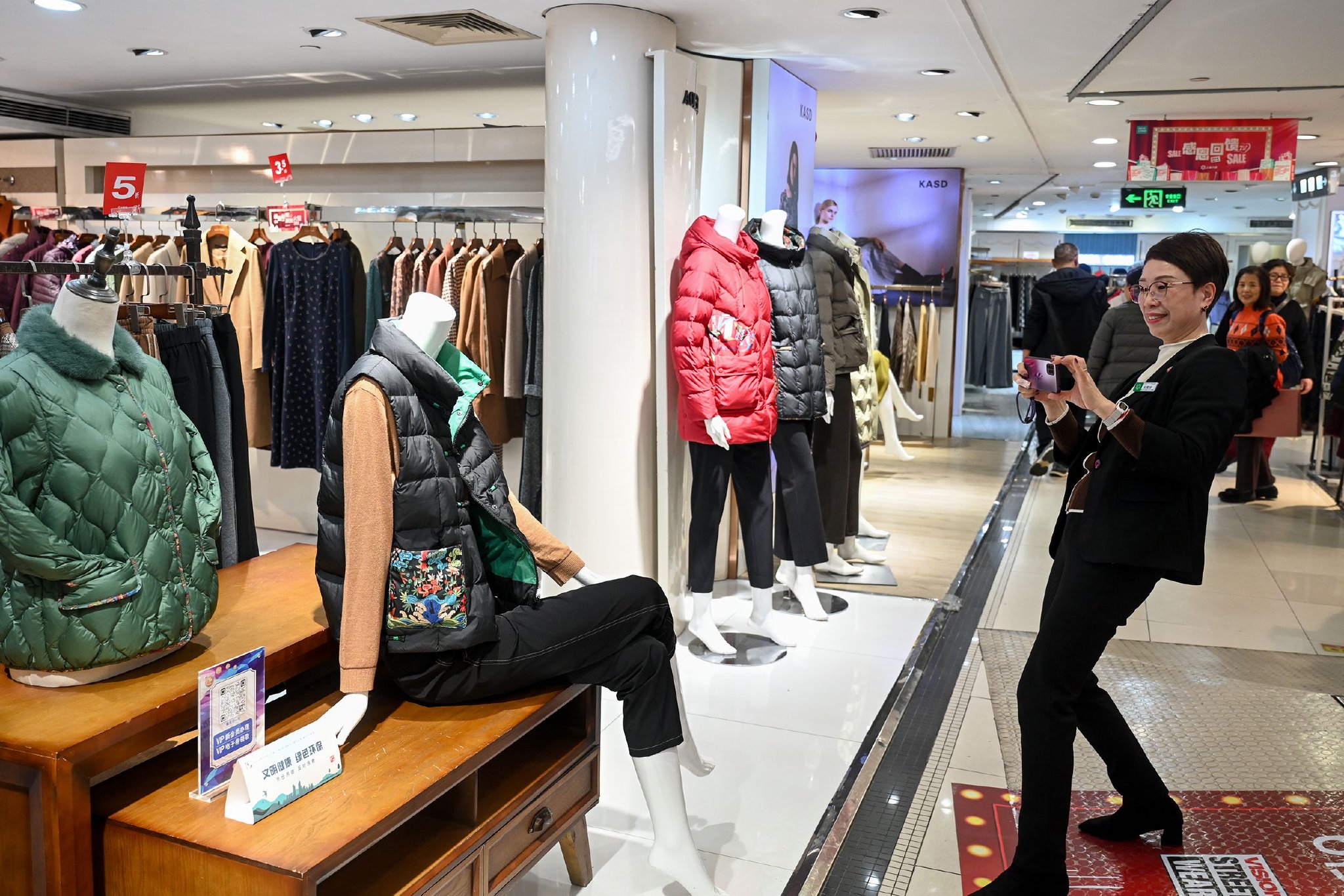 吴菊珍用手机拍摄自己工作的服装店内场景。