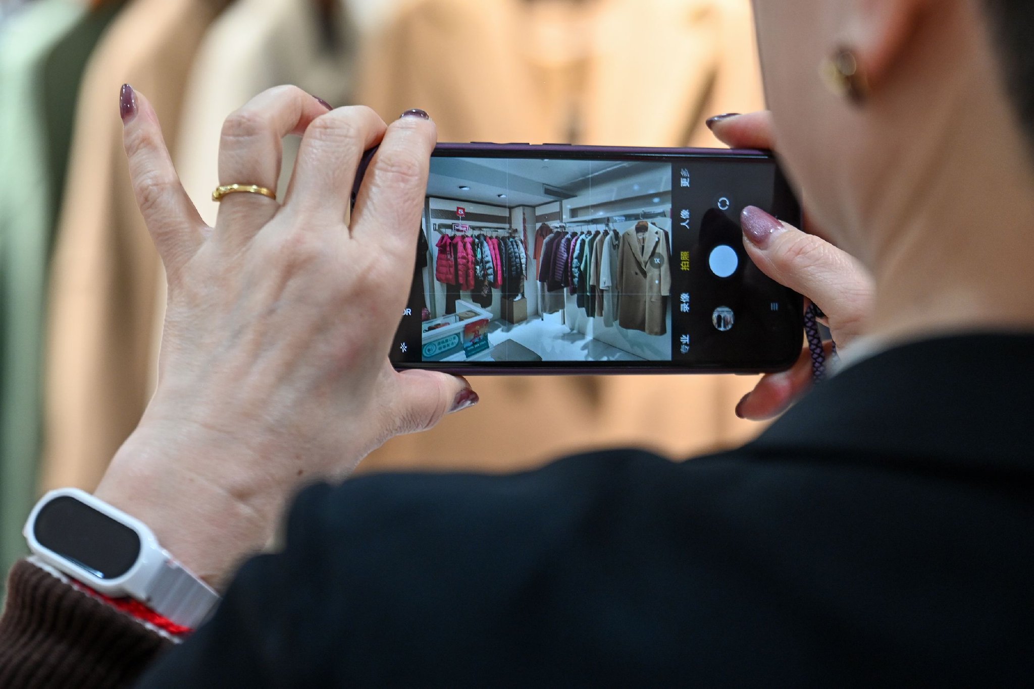 吴菊珍用手机拍摄自己工作的服装店内场景。