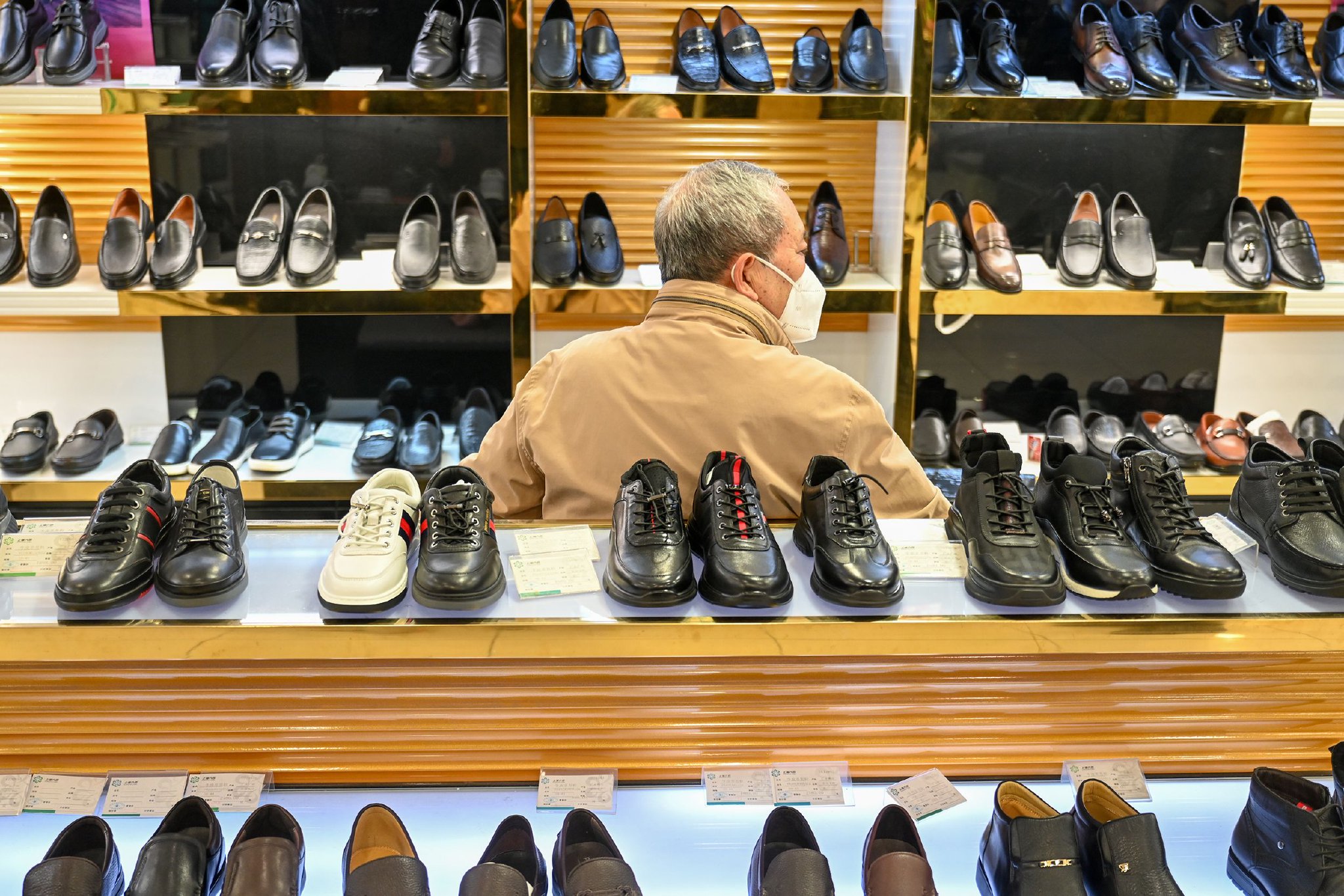 一位老人坐在鞋子店内休息。