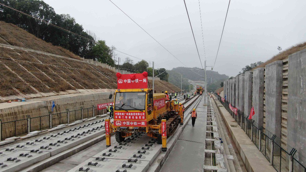 坑大桥施工现场,新型多功能牵引车将一对500米长钢轨铺设在无砟道床上