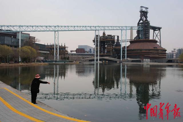 3月18日，北京首钢园秀池旁，一名正在喂鱼的游客。田嘉硕/摄