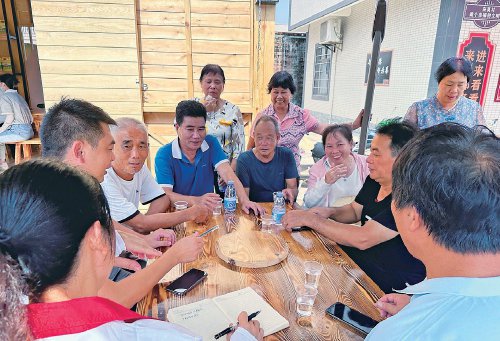 坡头区龙头镇莫村村干部与村民在"咱村铺仔"前商议球场升级改造等事项