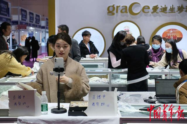 中心一处珠宝展位,工作人员利用柜台搭建了简易直播间进行直播带货