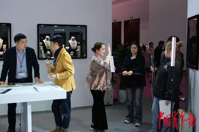 北京国家会议中心一处珠宝展位,工作人员手持设备进行直播带货