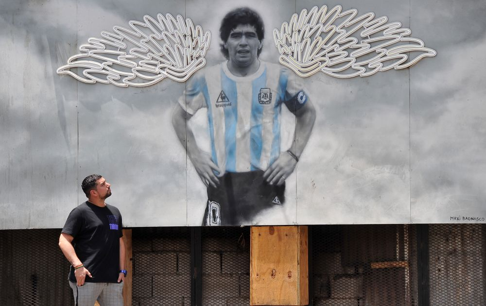 2021年11月25日，一名男子站在阿根廷街头马拉多纳的街头壁画前。新华社发
