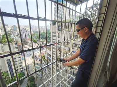 施工人员正用切割机在封闭的防盗网上打开一个窗口