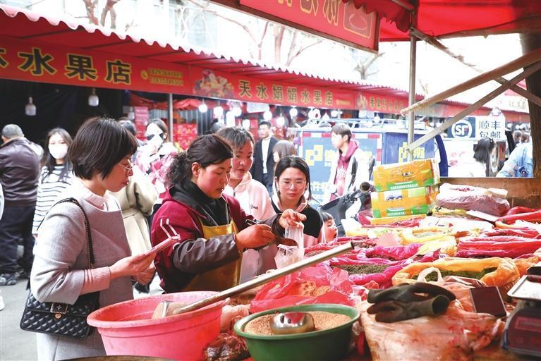 游客在天水市秦州区的一条小吃街购买辣椒面等土特产 □新华社照片