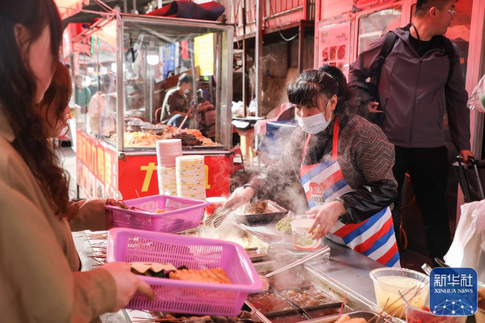 在天水市秦州区的一条小吃街,一个麻辣烫摊位的摊主在制作麻辣烫.