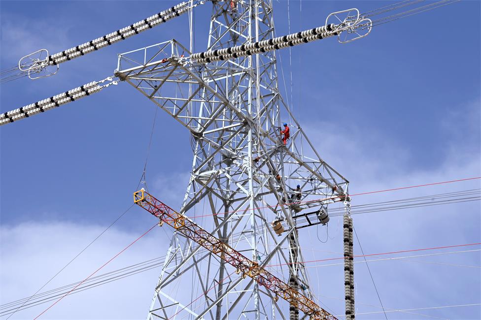 巴州-铁干里克-若羌750千伏线路工程跨越施工现场，作业人员在铁塔上安装附件。马元 摄