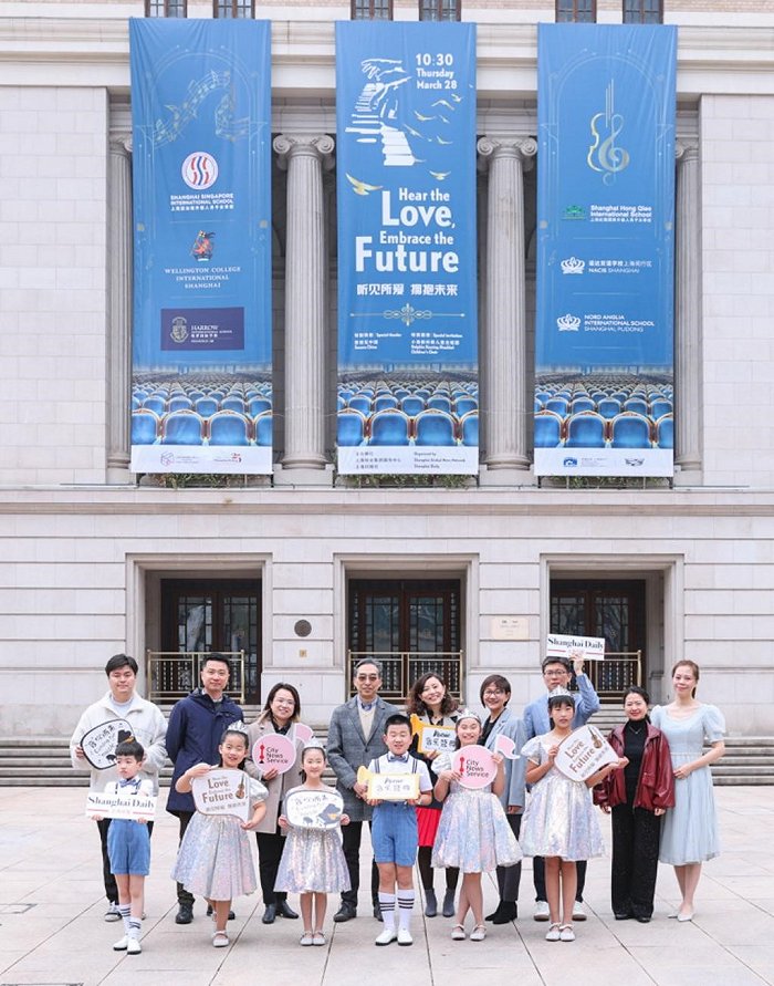 参加“听见所爱·拥抱未来”慈善音乐会的嘉宾和天津小海豚听障儿童合唱团的成员在上海音乐厅巨幅海报前合影留念。​​​