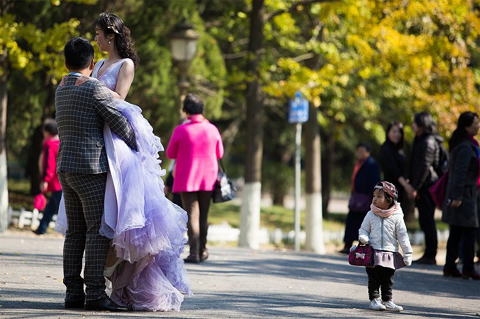 2016年10月，青岛八大关景区，拍摄婚纱照的新人吸引了小朋友的注意。 毕天宇摄