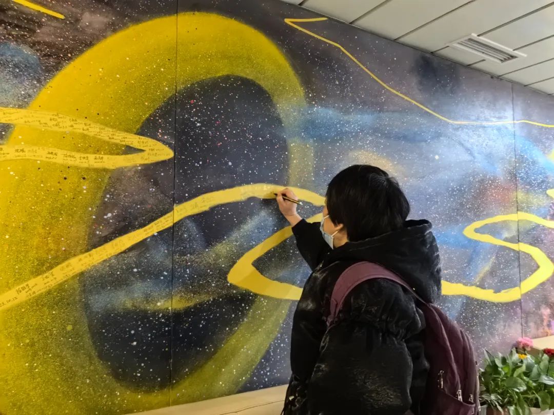 患者家属替离世的家人在《生命的长河》油画上写下名字